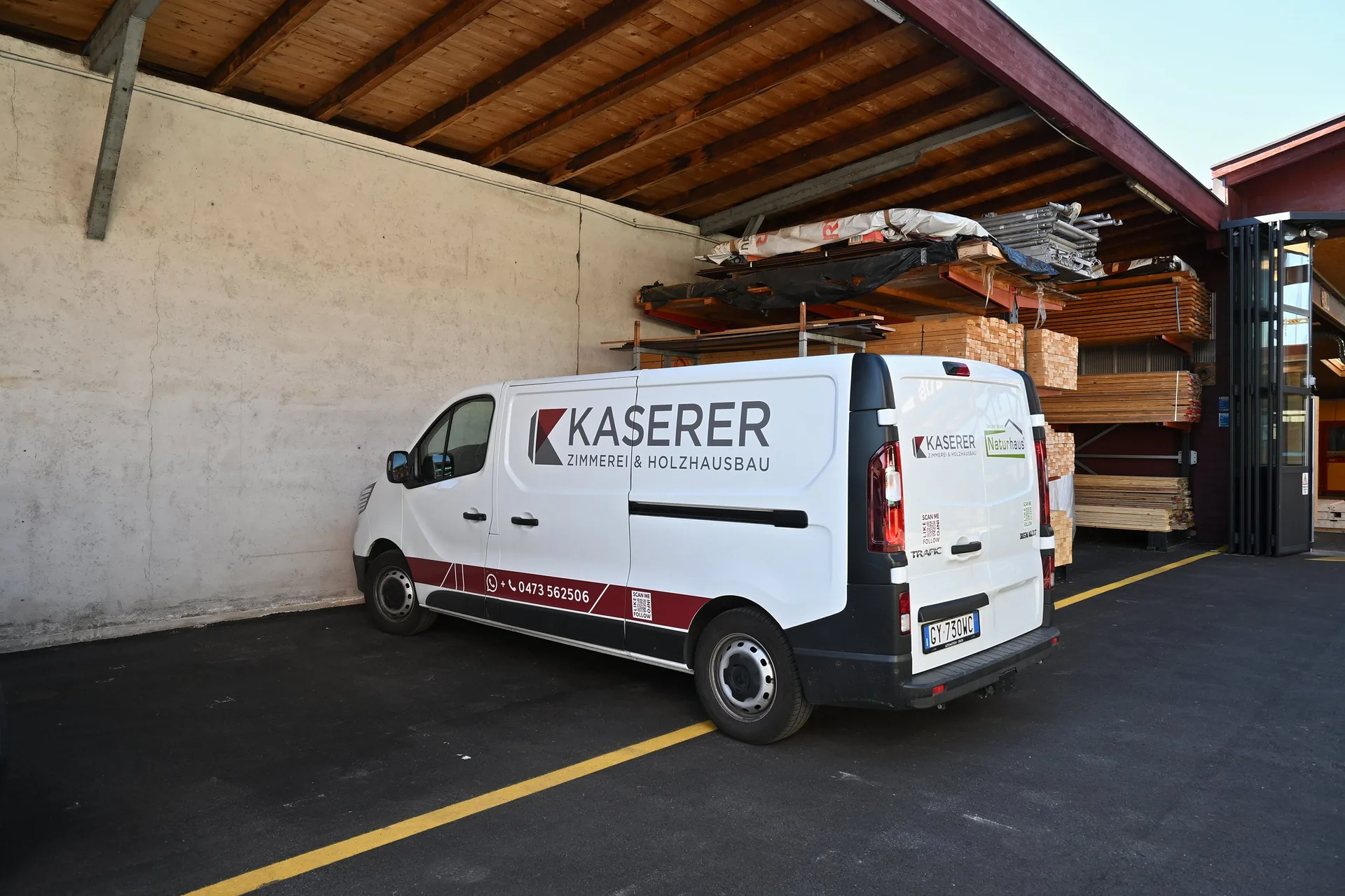 Weißer Kaserer-Transporter unter dem Dach des Holzlagers