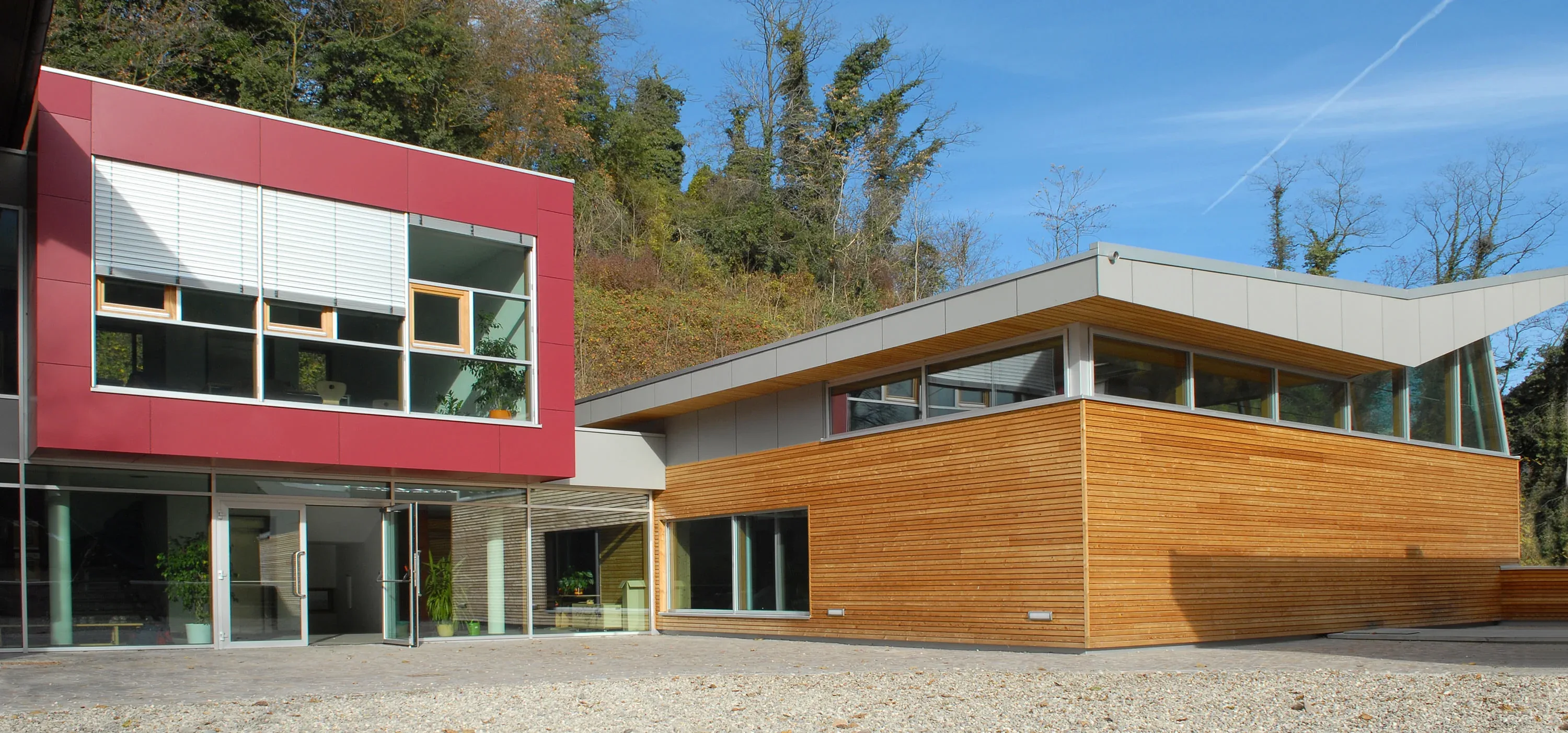 Gewerbebau mit Flachdach, roter Plattenfassade und Lärchenschalung