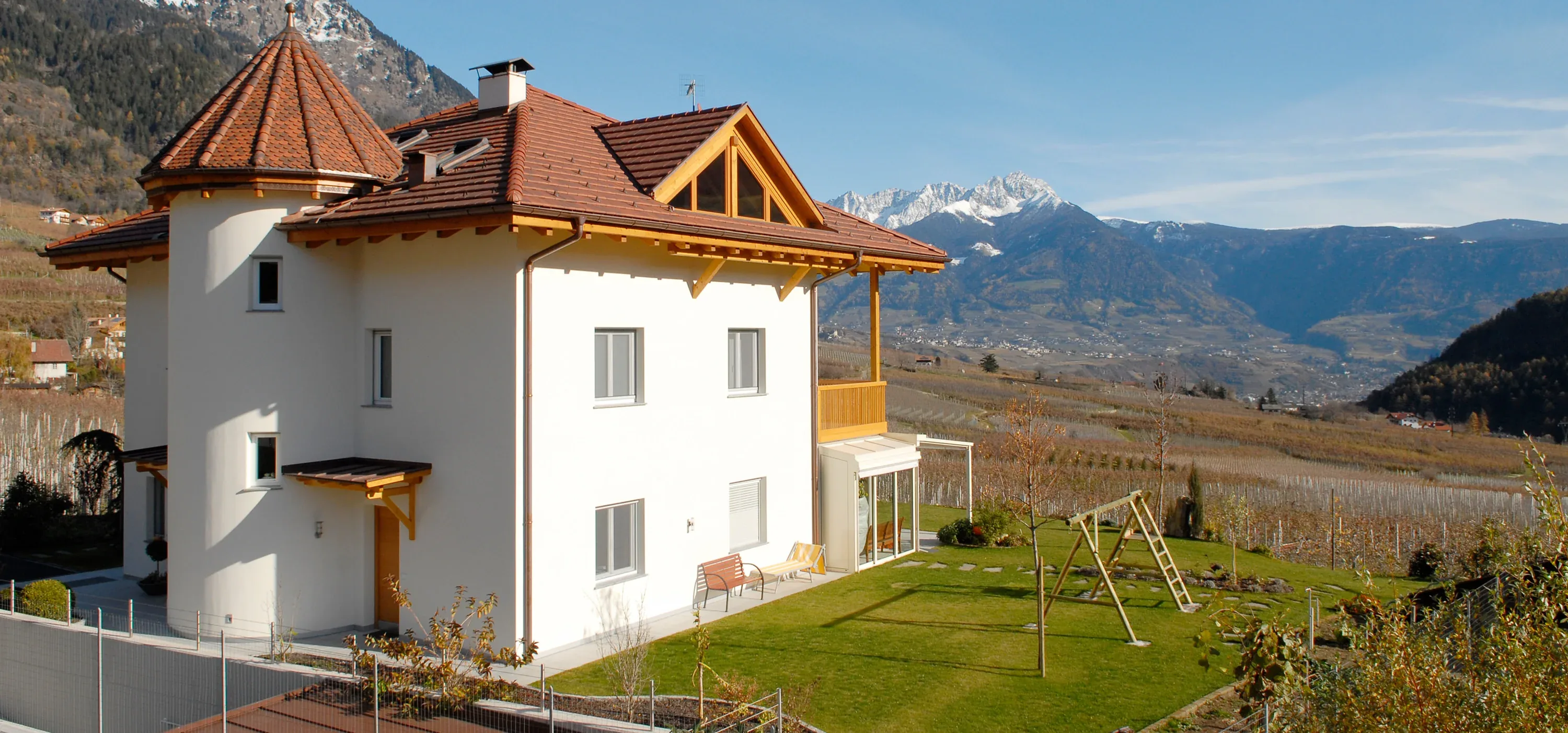 Ziegelgedecktes Steildach mit Turmhaube über einem weißen Wohnhaus