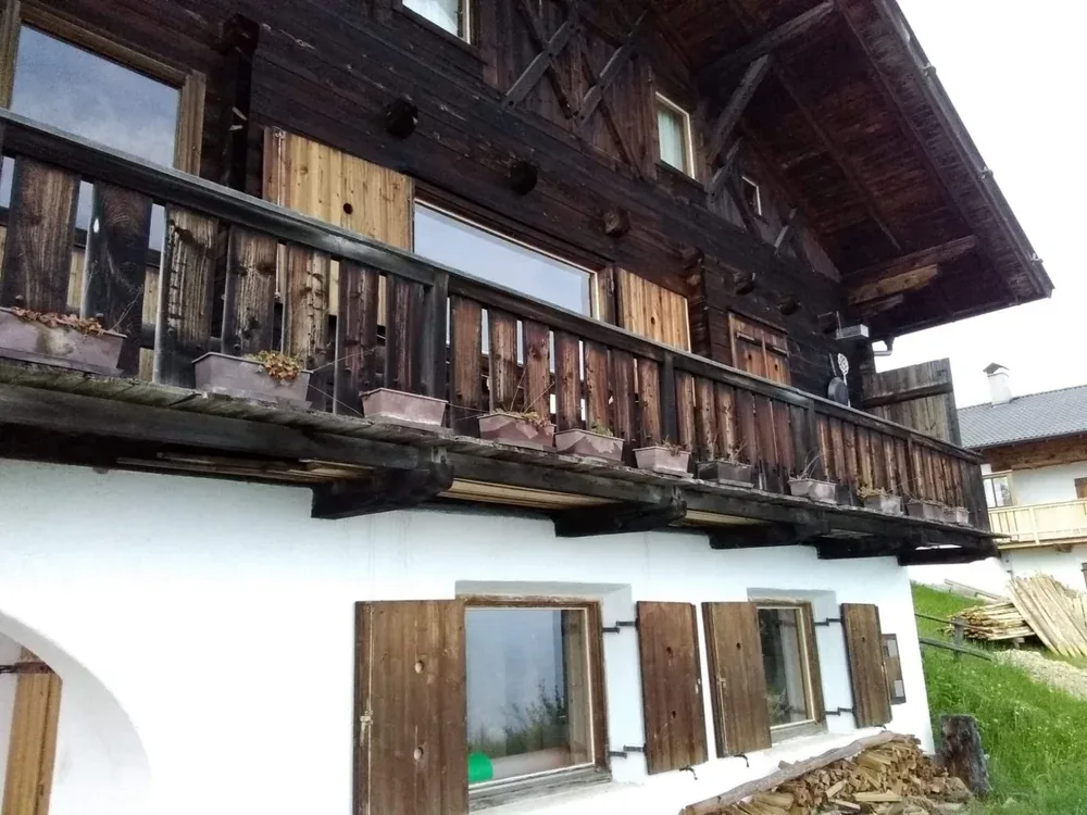 Verwitterter Holzbalkon mit Blumenkisten vor der Sanierung