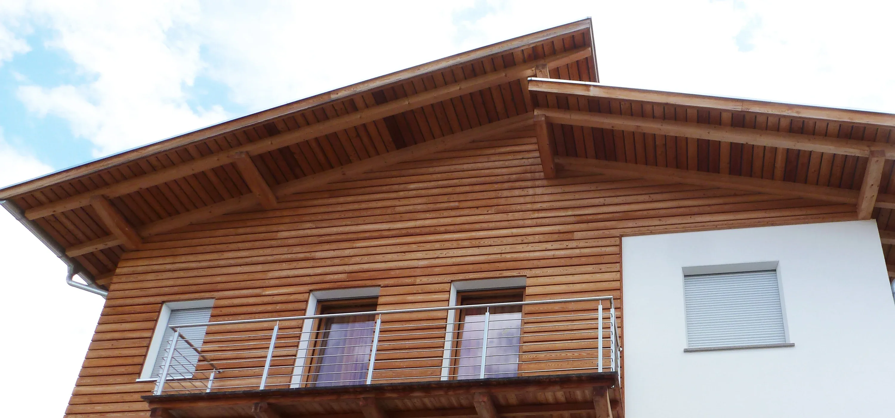 Giebel eines Holzhauses von unten, sichtbare Pfetten und Dachschalung